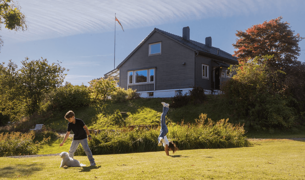 To barn som leker seg i hagen bak huset.